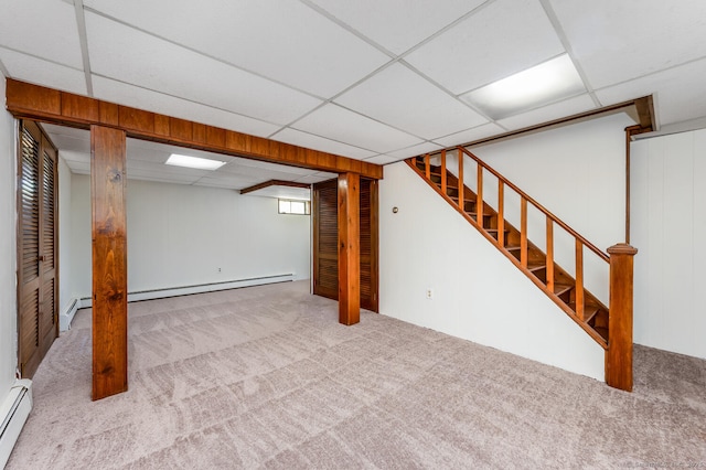 basement featuring baseboard heating, carpet flooring, stairs, and a paneled ceiling