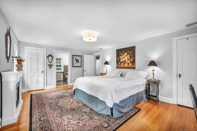 10 Meadowbrook Rd, Hamden, CT 06517 - bedroom with radiator heating unit, light wood-style flooring, a fireplace, baseboards, and ensuite bathroom