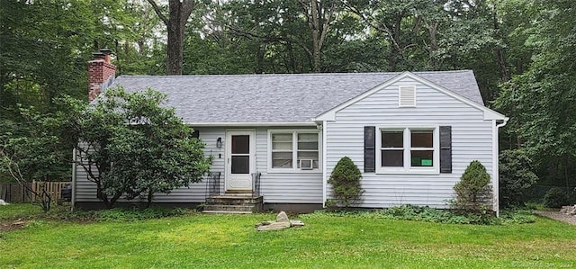 view of front of house with entry steps, a front yard, a chimney, and a shingled roof