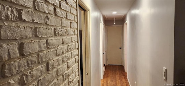 corridor featuring attic access and wood finished floors