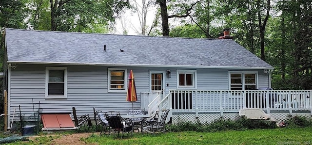 rear view of property featuring a wooden deck, a shingled roof, and a chimney