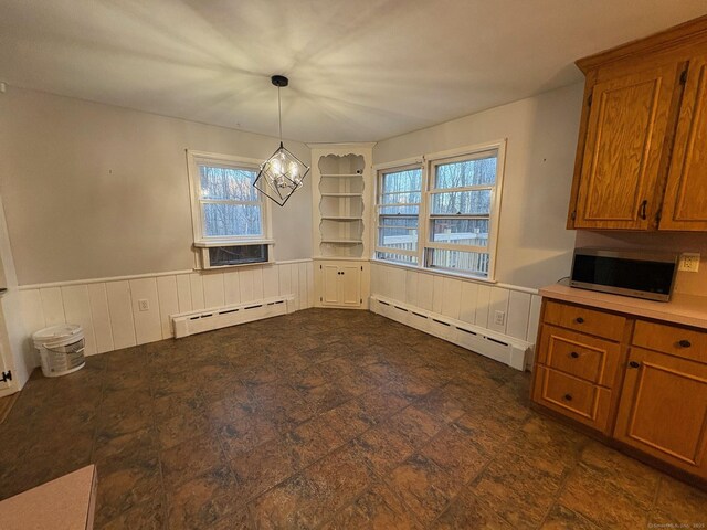 unfurnished dining area with baseboard heating, a wainscoted wall, and built in features