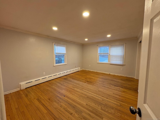 spare room featuring a baseboard heating unit, ornamental molding, plenty of natural light, wood finished floors, and recessed lighting