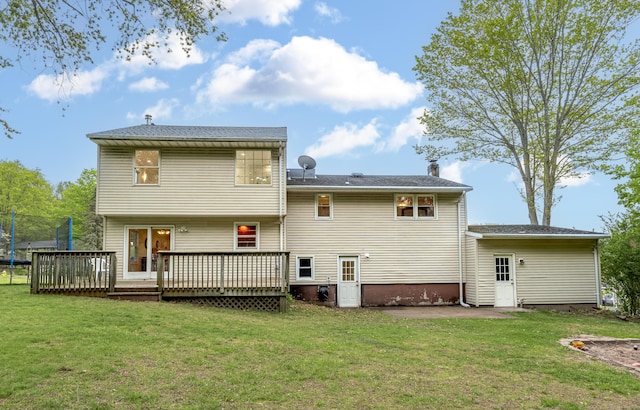 rear view of house featuring a trampoline, a patio area, a lawn, and a deck
