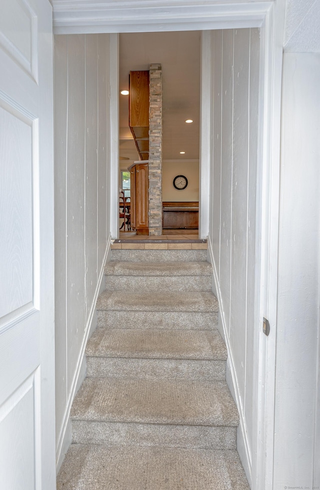 stairs featuring carpet floors, baseboards, and wood walls