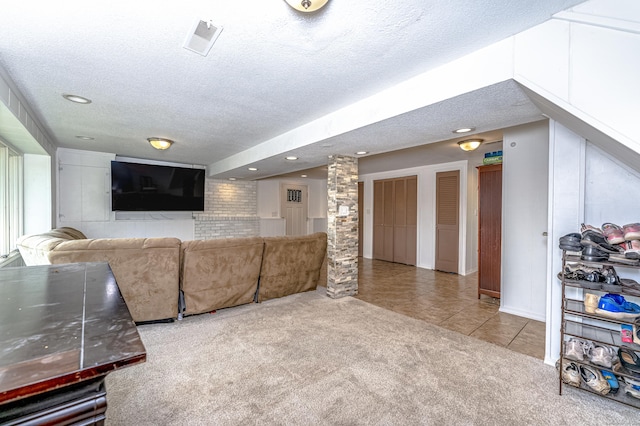 tiled living room with a textured ceiling, carpet, ornate columns, and recessed lighting