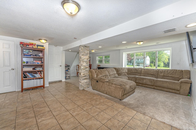 living room with ornate columns, a textured ceiling, and light tile patterned floors