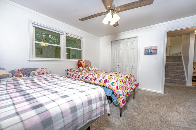 carpeted bedroom with a closet, ceiling fan, baseboards, and ornamental molding