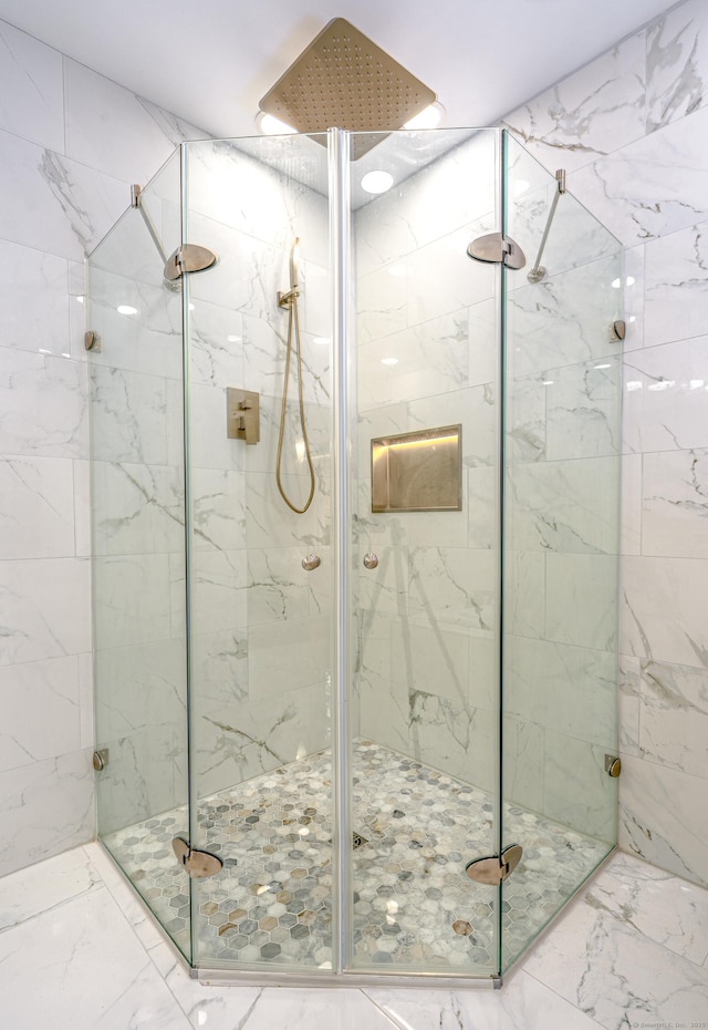 full bath featuring a marble finish shower and marble finish flooring