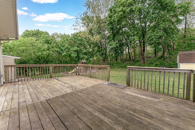 wooden terrace featuring a storage shed, an outbuilding, and a yard