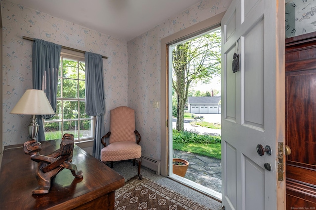 living area with wallpapered walls, healthy amount of natural light, and baseboard heating