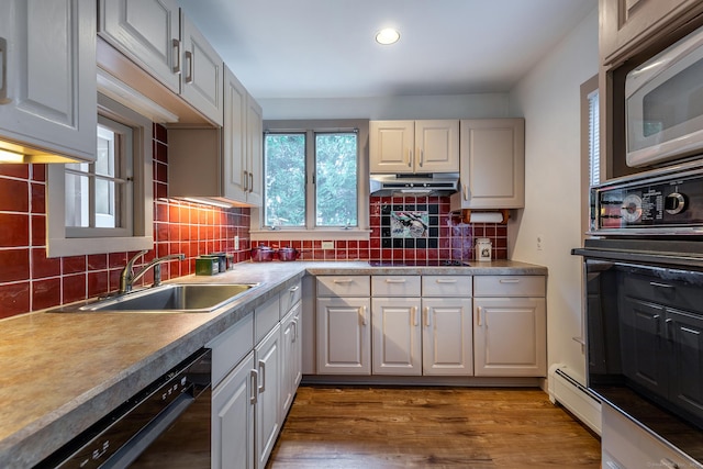 kitchen with a sink, black appliances, tasteful backsplash, wood finished floors, and recessed lighting