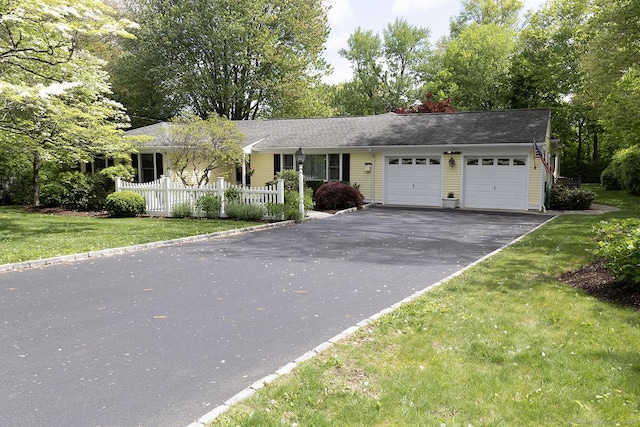 ranch-style home featuring a garage and asphalt driveway
