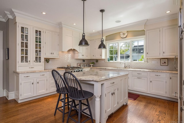 37 Lantern Hill Rd, Madison, CT 06443 - kitchen with a kitchen bar, wood finished floors, white cabinets, a center island, and ornamental molding
