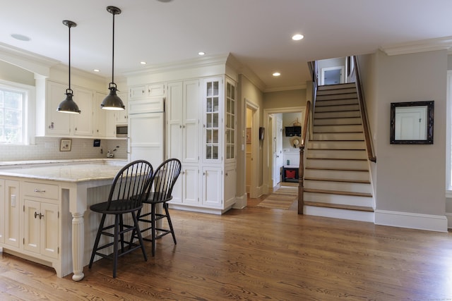 37 Lantern Hill Rd, Madison, CT 06443 - kitchen featuring wood finished floors, white cabinetry, a breakfast bar area, light stone counters, and glass insert cabinets