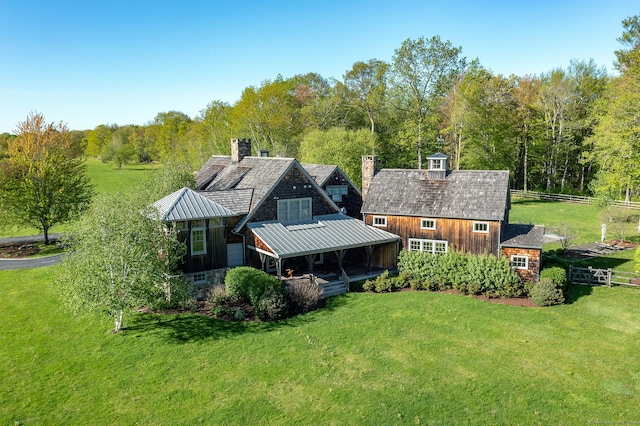 back of house with a standing seam roof, a chimney, metal roof, and an outbuilding