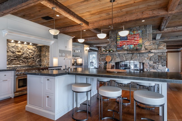 kitchen with wooden ceiling with exposed beams, high end stainless steel range oven, dark countertops, dark wood-type flooring, and white cabinets