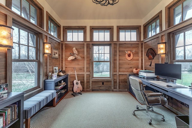 carpeted office with wooden walls, plenty of natural light, and lofted ceiling