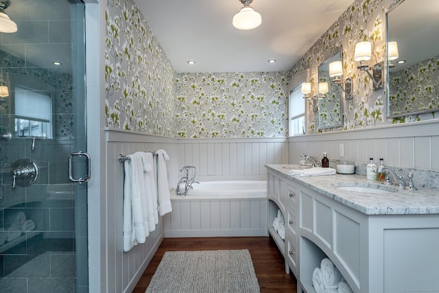 bathroom with wallpapered walls, wood finished floors, a stall shower, wainscoting, and a garden tub