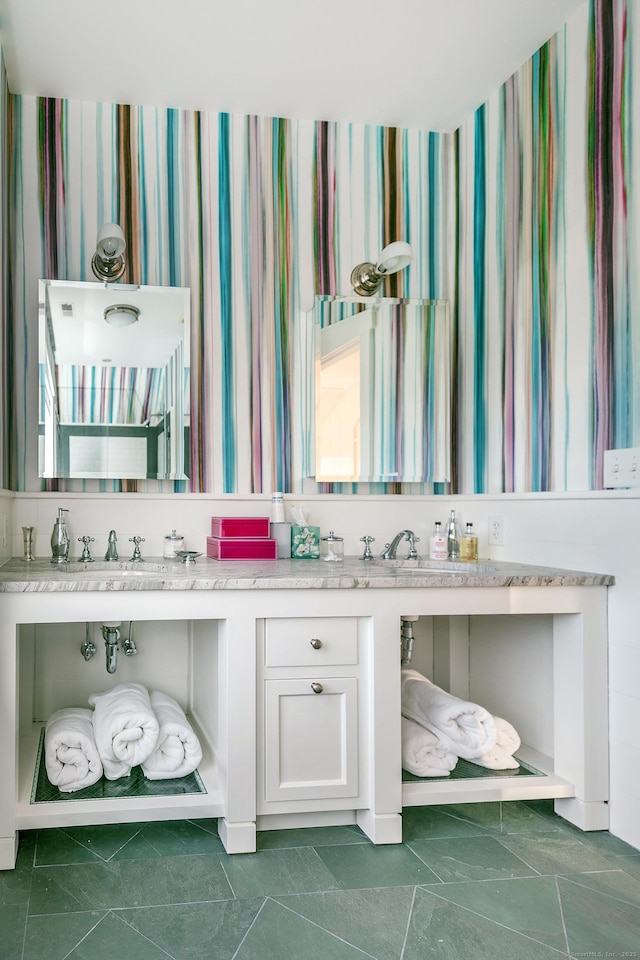 bathroom with wallpapered walls and double vanity