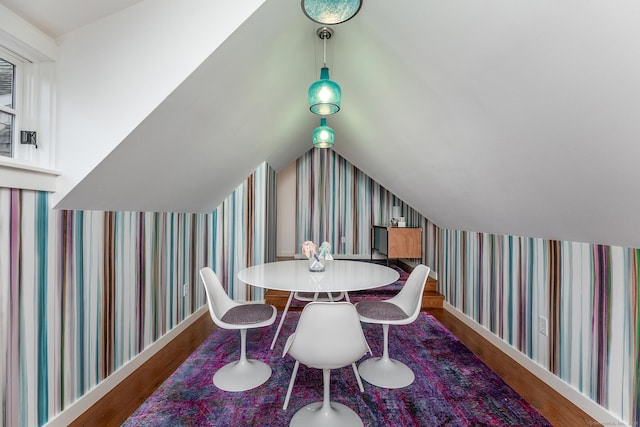 dining room with wallpapered walls, wood finished floors, and vaulted ceiling