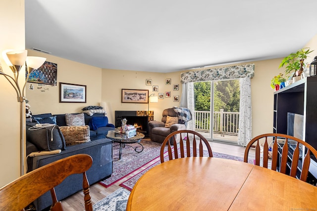 dining space with wood finished floors and a warm lit fireplace