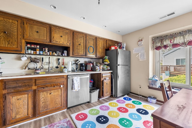kitchen with stainless steel appliances, light wood-style flooring, brown cabinetry, light countertops, and open shelves