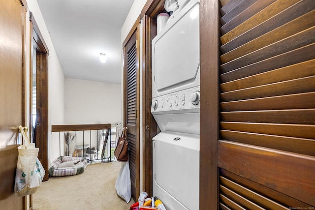 clothes washing area with stacked washer and clothes dryer and carpet