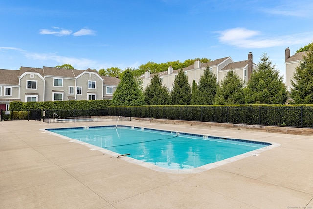 community pool featuring fence, a residential view, and a patio