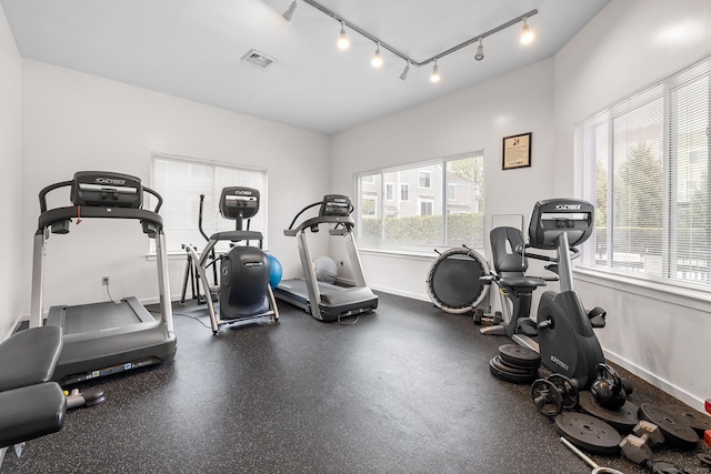 exercise room featuring rail lighting and baseboards