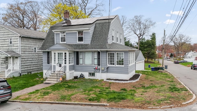 colonial inspired home with entry steps, roof mounted solar panels, a gambrel roof, roof with shingles, and a chimney