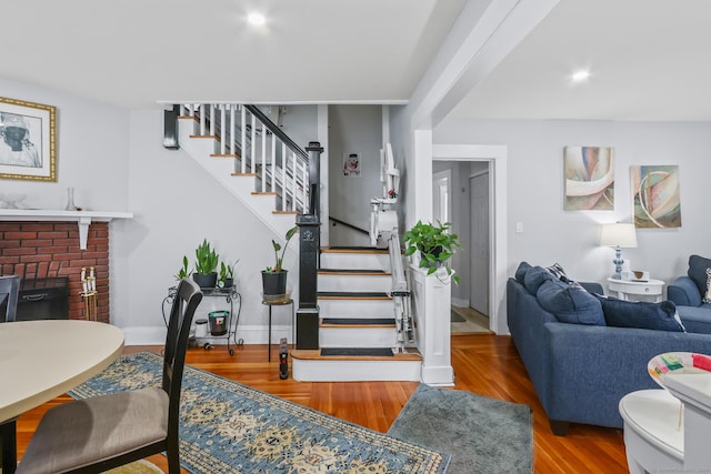 stairway with a brick fireplace and wood finished floors