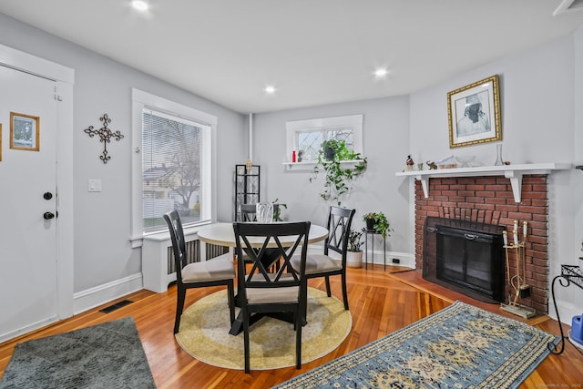dining space with wood finished floors, recessed lighting, baseboards, and a brick fireplace