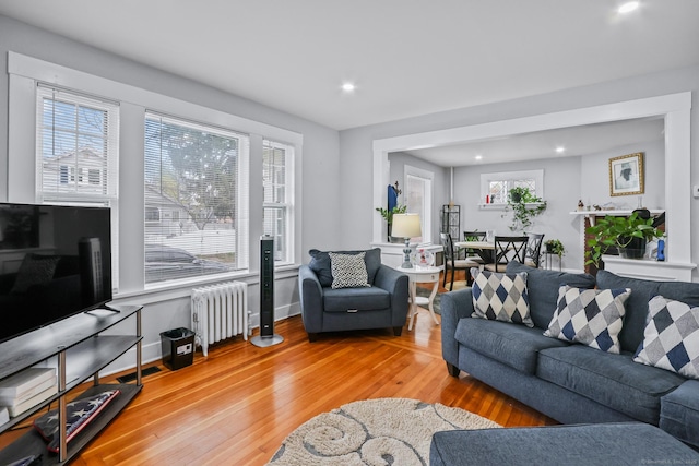 living area with radiator, light wood-type flooring, plenty of natural light, recessed lighting, and baseboards