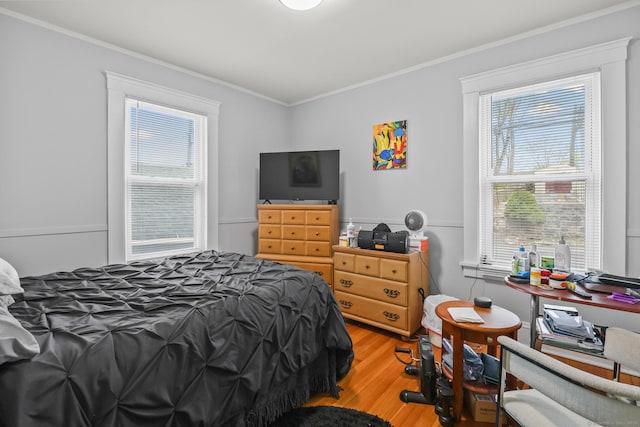 bedroom featuring ornamental molding, wood finished floors, and multiple windows