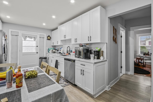 kitchen featuring stainless steel appliances, a sink, light countertops, light wood-type flooring, and white cabinets