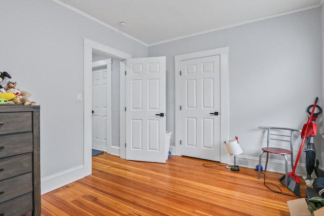 bedroom with light wood-style floors, ornamental molding, and baseboards