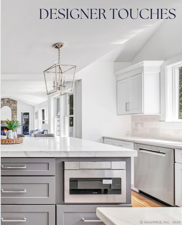 706 Judd St, Fairfield, CT 06825 - kitchen with appliances with stainless steel finishes, vaulted ceiling, a chandelier, gray cabinetry, and light stone counters