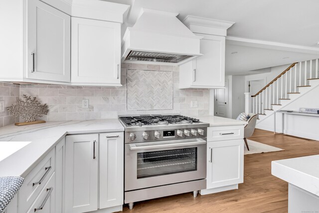 706 Judd St, Fairfield, CT 06825 - kitchen featuring stainless steel stove, premium range hood, light wood finished floors, and white cabinets