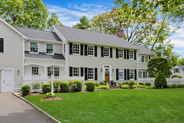 colonial home featuring a chimney and roof with shingles