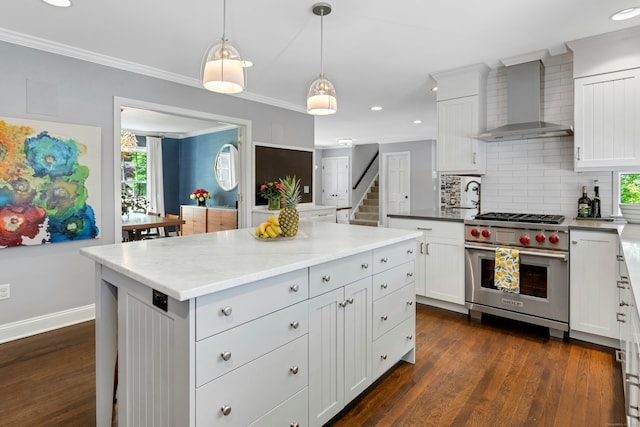 kitchen with wall chimney range hood, luxury stove, recessed lighting, a kitchen island, and tasteful backsplash