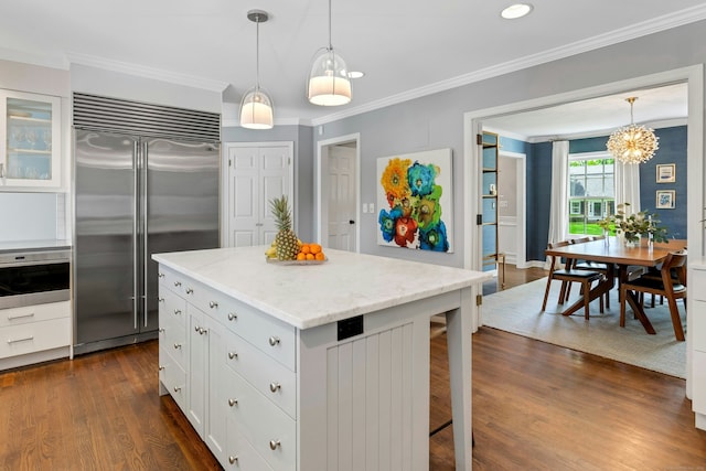 kitchen featuring stainless steel appliances, a kitchen breakfast bar, white cabinets, dark wood-type flooring, and ornamental molding