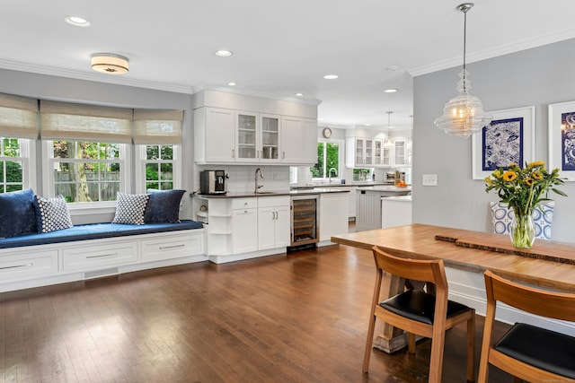 kitchen featuring wine cooler, crown molding, glass insert cabinets, tasteful backsplash, and white cabinetry