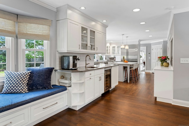 kitchen with a sink, wine cooler, ornamental molding, backsplash, and stainless steel built in refrigerator