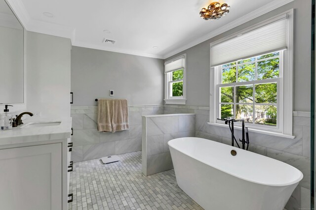 full bath with tile walls, a freestanding tub, crown molding, vanity, and tile patterned floors