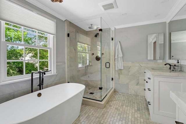 bathroom featuring tile walls, healthy amount of natural light, vanity, a shower stall, and a soaking tub