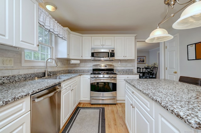 539 Plains Rd, Milford, CT 06461 - kitchen featuring stainless steel appliances, a sink, light wood finished floors, backsplash, and white cabinets