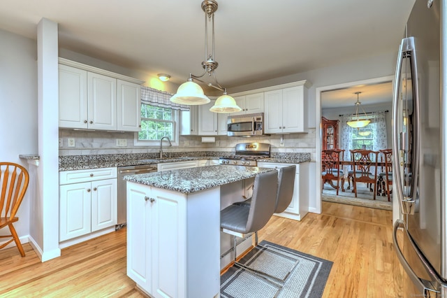 539 Plains Rd, Milford, CT 06461 - kitchen featuring stainless steel appliances, light wood-style flooring, white cabinetry, tasteful backsplash, and a center island