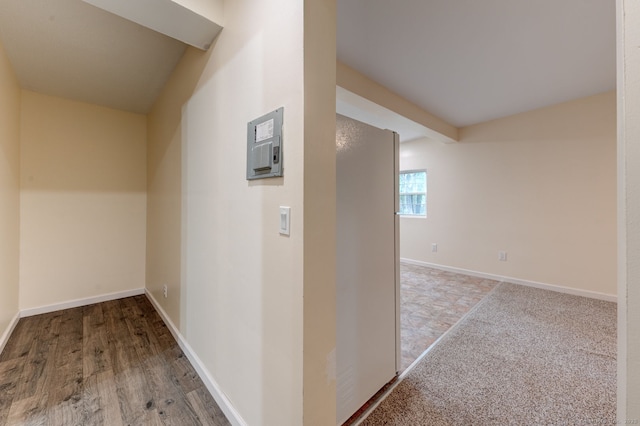corridor with baseboards and electric panel