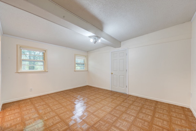 empty room with beamed ceiling, a textured ceiling, and baseboards
